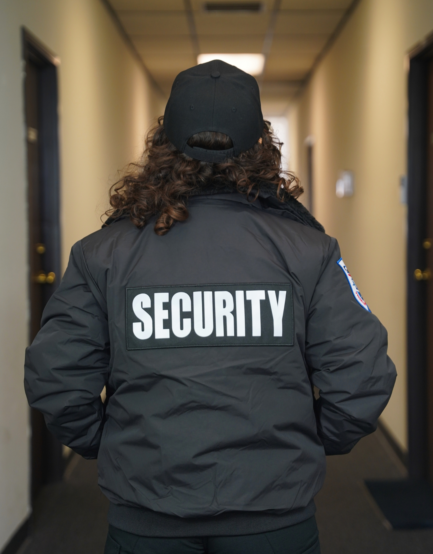 Luminex residential officer walking an interior hallway with SECURITY marked across the jacket back