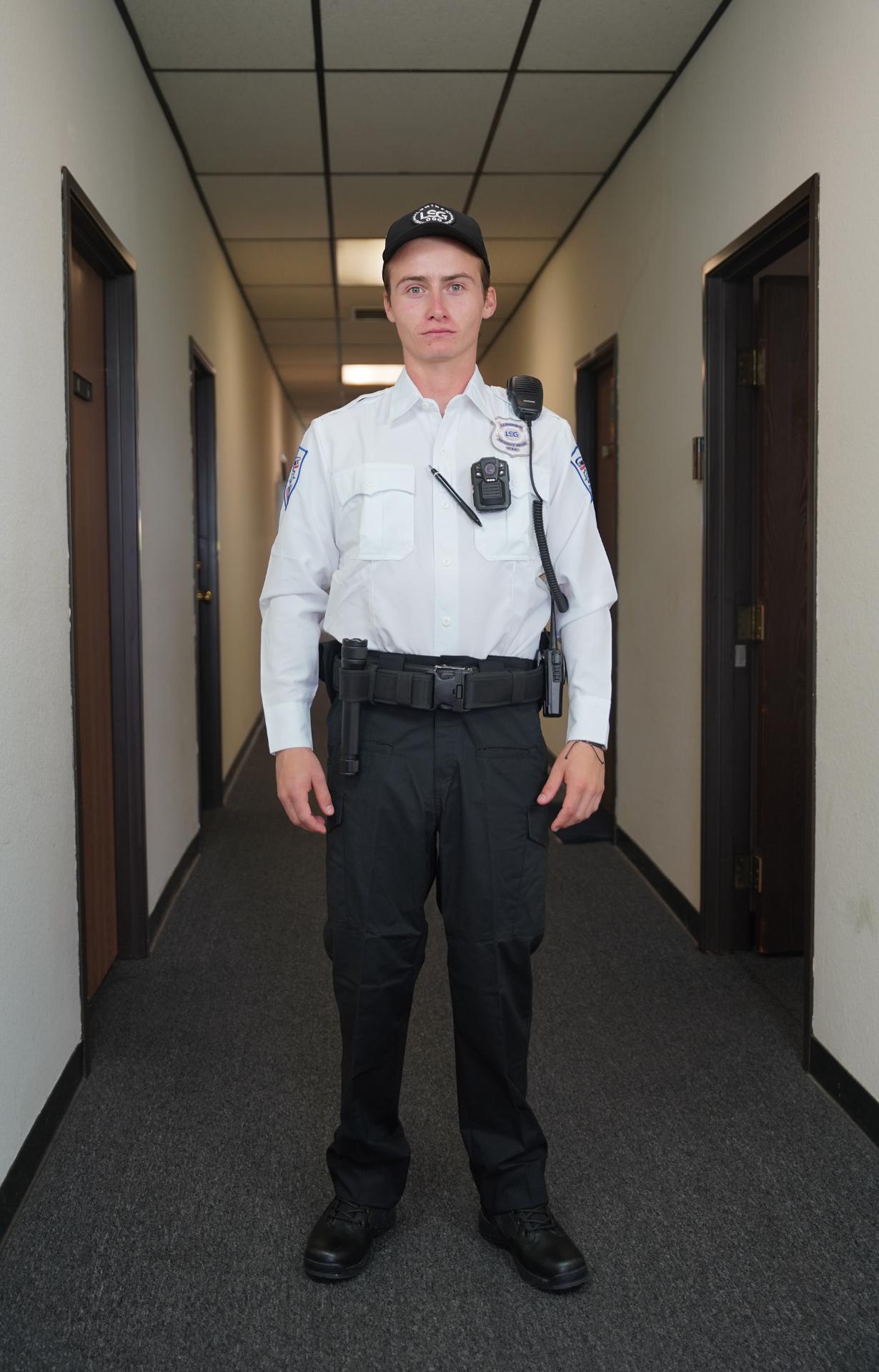 Luminex officer in white class A shirt with duty belt and body camera in interior corridor