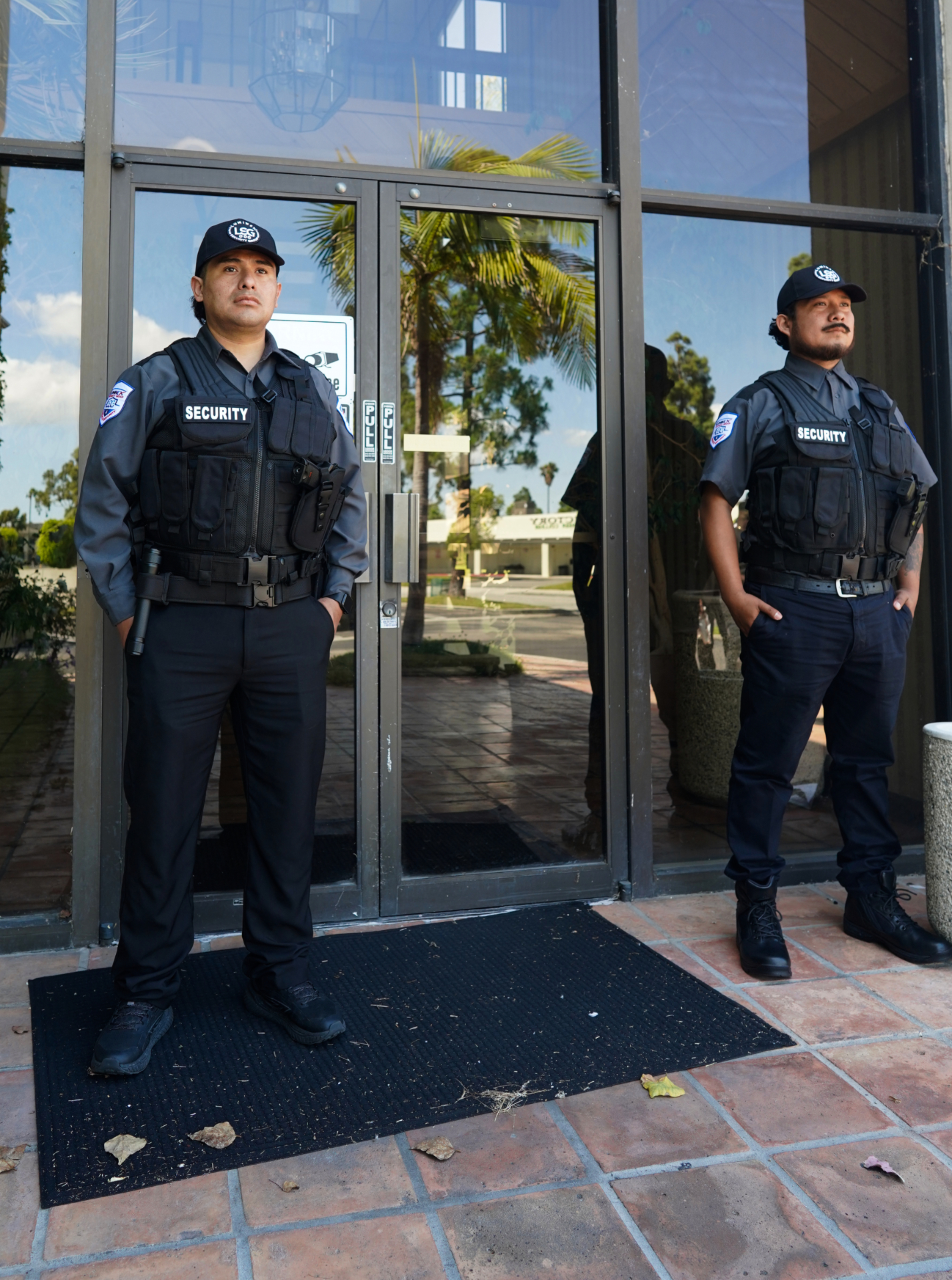 Two Luminex tactical officers posted at a glass entrance, ready to engage visitors